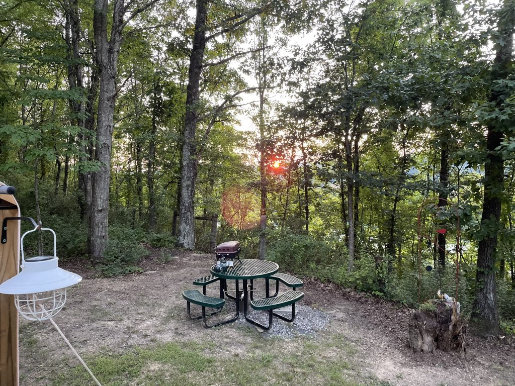 hilltop sunrise urban camping wall-side tent at night new river gorge bridge summit Bechtel reserve boy scout camp Fayette county Fayetteville oak hill hilltop WV West Virginia tent deck with planters, ferns and picnic table sunset